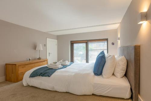 um quarto branco com uma cama grande e almofadas azuis em Gorgeous loft style 3BR apt, Battersea em Londres
