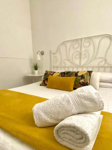 1 dormitorio con 1 cama blanca con manta amarilla en Alvorada Rooms, en Palermo