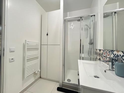 une salle de bain blanche avec une douche et un lavabo dans l'établissement Chic in Paris - Oberkampf, à Paris