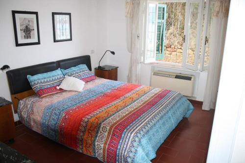 a bedroom with a bed with a colorful blanket and a window at Casa sul mare in Procchio