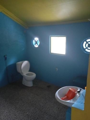 a blue bathroom with a toilet and a window at sunrise seasports in Iboih