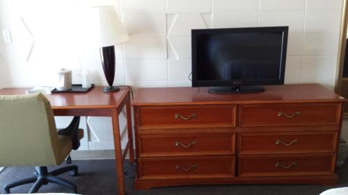 a television on a dresser with a desk and a deskablish at Dakota Inn in Huron