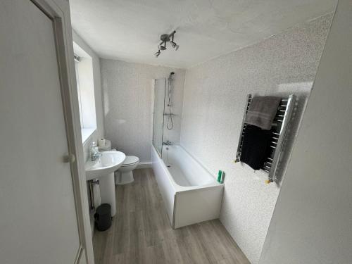 a bathroom with a sink and a tub and a toilet at Holly House- 2 Bed in Whitehaven