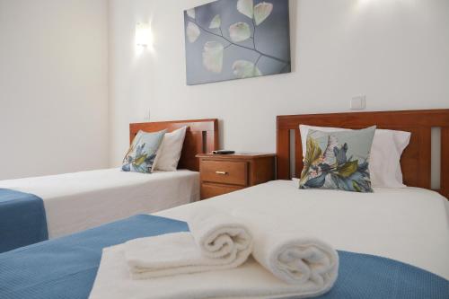 a bedroom with two beds with white sheets at Casa do Castelo in Reguengos de Monsaraz