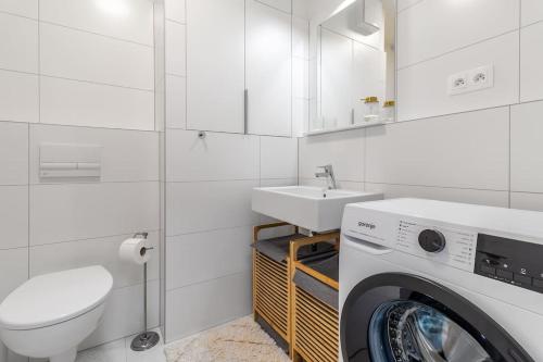 baño blanco con lavadora y lavamanos en Cozy apartment near city centrum and Bratislava airport en Prievoz