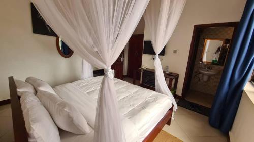 a bedroom with a bed with white curtains and a sink at Mountain Inn Hotel in Mbale