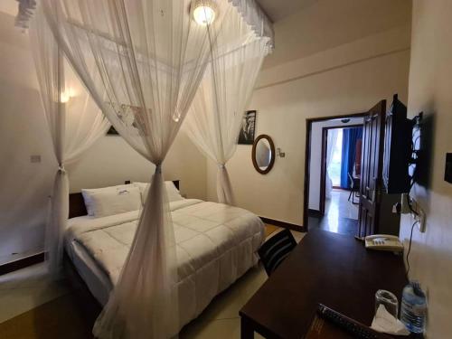 1 dormitorio con 1 cama con cortinas y mesa en Mountain Inn Hotel, en Mbale