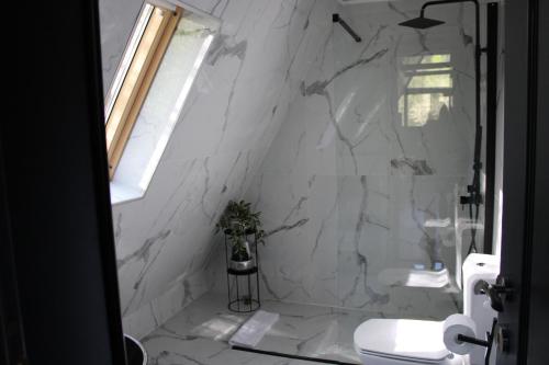a bathroom with white marble walls and a toilet at Valea Mosului - Cozy A Frame in Petroşani