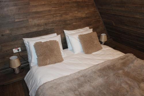 a bed with white sheets and pillows in a bedroom at Valea Mosului - Cozy A Frame in Petroşani