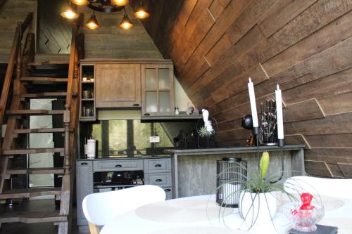 a kitchen with wooden walls and a table with white chairs at Valea Mosului - Cozy A Frame in Petroşani