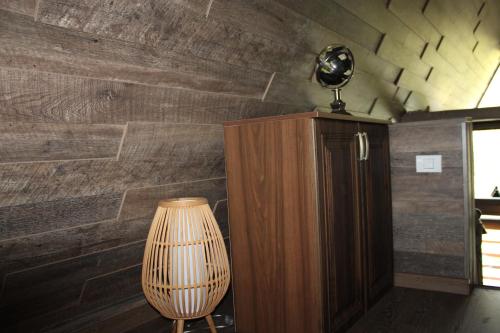 a room with a lamp and a wooden wall at Valea Mosului - Cozy A Frame in Petroşani