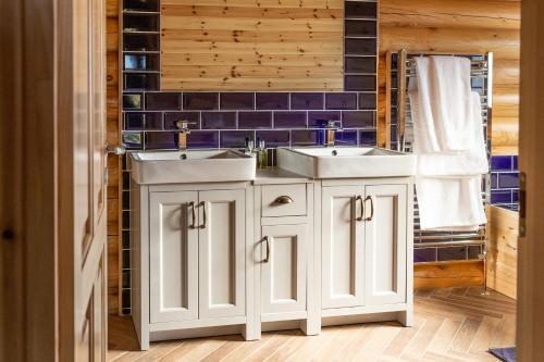 a bathroom with two sinks and a blue tiled wall at Owl's Nest in Foxton