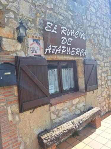 a building with two windows and a sign on it at El Rincón de Atapuerca in Atapuerca