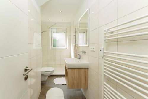 een witte badkamer met een wastafel en een toilet bij Linz SUNNY in Linz