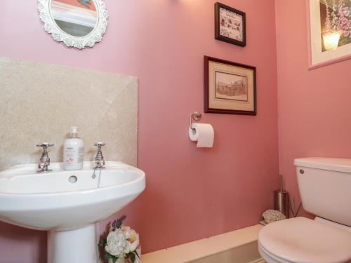 a pink bathroom with a sink and a toilet at The Old Byre in Salisbury