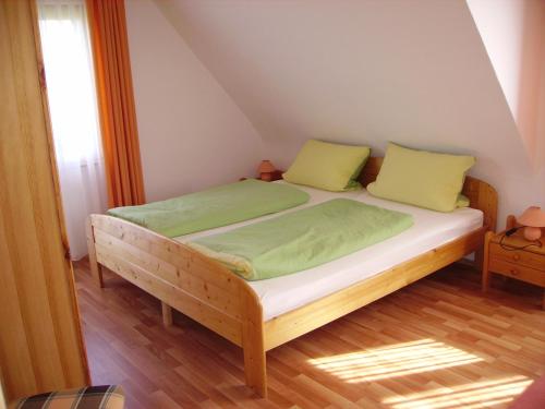 a bed with green sheets and yellow pillows in a room at Äckerhof in Wolfach