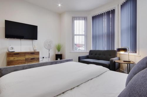 a bedroom with a bed and a tv and a chair at Ashley Road Apartment 1 in Poole