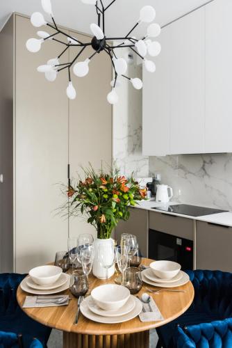 a dining room table with plates and glasses and a chandelier at Sol Marina Resort Wyspa Sobieszewska II - LoftAffair Collection in Wiślinka