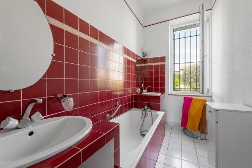 - une salle de bains rouge et blanche avec baignoire et lavabo dans l'établissement la Voûte, à Carcassonne