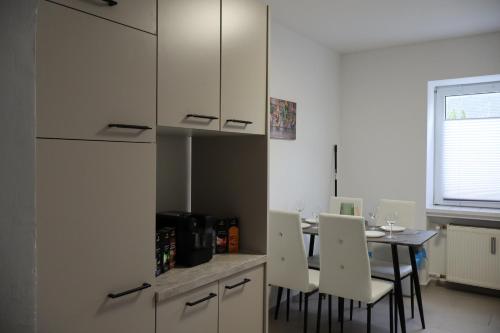 a kitchen with a table and white cabinets at Hirsch24- 6 Betten -Apartment in Lippstadt