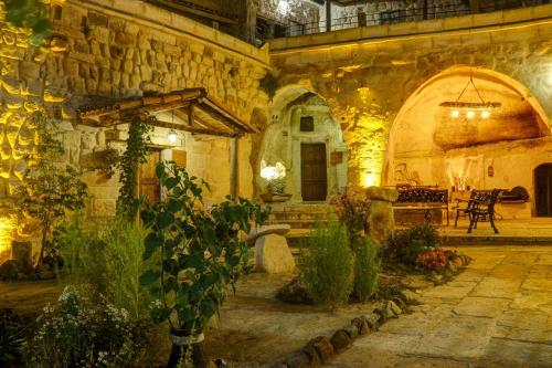 a large stone building with a courtyard with plants at Gibos Cave Hotel in Urgup