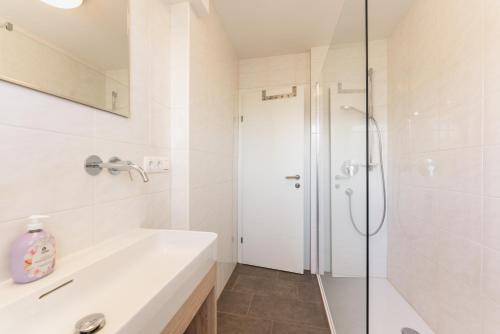 ein weißes Bad mit einem Waschbecken und einer Dusche in der Unterkunft Linz CITY in Linz