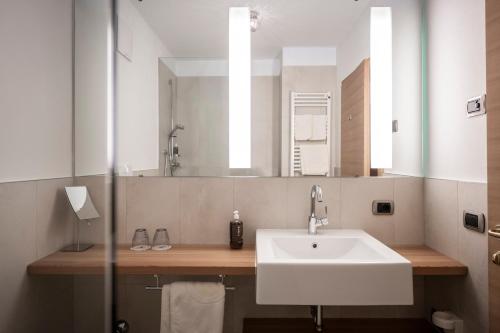 ein Bad mit einem Waschbecken und einem Spiegel in der Unterkunft Hotel & Gasthof zum Hirschen in Jenesien