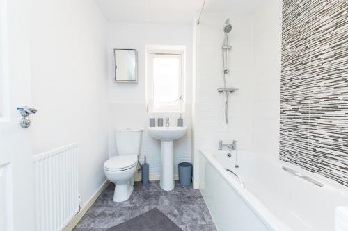 Baño blanco con aseo y lavamanos en Free Parking 3 Bedroom House in Nottingham, en Nottingham