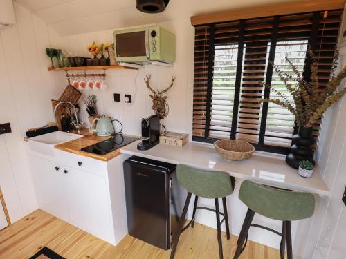 a kitchen with a counter and two stools in it at Limetree Luxury Glamping Southdown in Retford