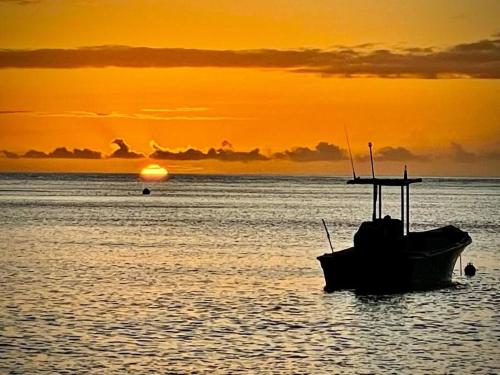 a boat sitting in the water at sunset at Terrasses de Saint Pierre - Papyrus in Saint-Pierre
