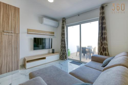 uma sala de estar com um sofá e uma televisão em Cosy 3BR Home with breathtaking views of St Pauls by 360 Estates em St. Paul's Bay