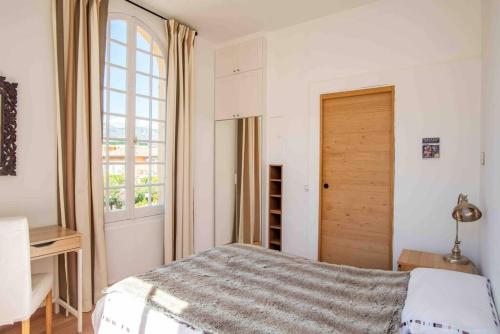 een witte slaapkamer met een bed en een raam bij The Cap - Charming apartment in Saint-Jean-Cap-Ferrat