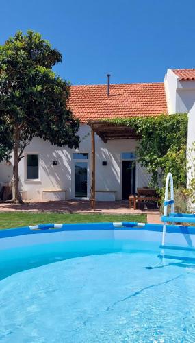 a swimming pool with a chair and a house at Casa Magana em Grândola in Grândola