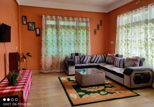 uma sala de estar com paredes cor de laranja e um sofá em Himali Homestay , Mirik em Mirik