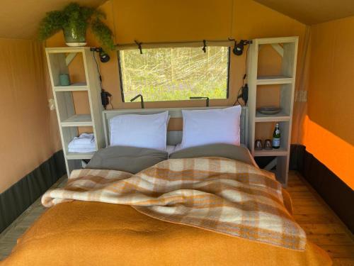 a bed with a blanket and a window in a room at Camping Zee van Tijd Holwerd in Holwerd