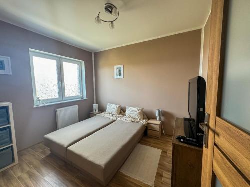 a bedroom with a bed and a flat screen tv at Apartament USTKA in Ustka