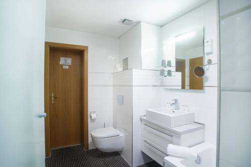 a white bathroom with a sink and a toilet at Spa Hotel Diana in Františkovy Lázně