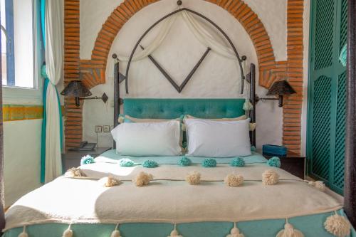 a bedroom with a large bed with a green headboard at Riad Al Madina in Essaouira