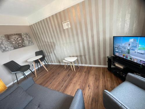 un soggiorno con divano, TV e sedie di Comfy One Bedroom Apartment a Darlaston