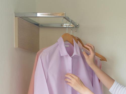 a woman is hanging a pink shirt on a hanger at HOP INN Kanchanaburi Building A in Kanchanaburi