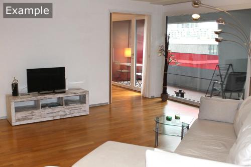 uma sala de estar com um sofá e uma televisão em Residenz Senevita Westside em Berna