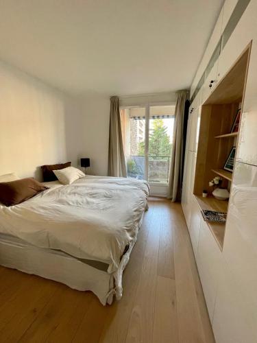 une chambre avec un lit et une grande fenêtre dans l'établissement Stylish modern large 2 Bedrooms 5 min close to Paris, à Levallois-Perret