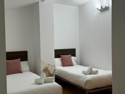 2 camas en una habitación con almohadas blancas y rosas en Wave Apartments, en Villajoyosa
