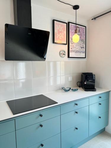 a kitchen with a blue dresser with a television on it at Ellens Have, Lejlighed Asta in Ebeltoft