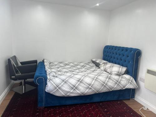 Cama azul en habitación con silla en Beautiful apartment in slough en Stoke Poges