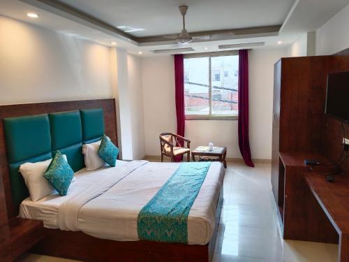 Hotel Tela Suite A Family Hotel Near Delhi Airport في نيودلهي: غرفة نوم بسرير كبير وتلفزيون