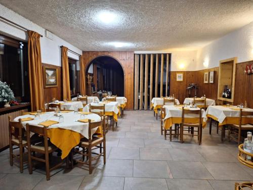 une salle à manger avec des tables blanches et des serviettes jaunes dans l'établissement hotel quai, à Monno