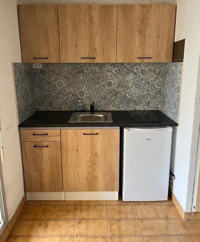 une cuisine avec un évier et un réfrigérateur blanc dans l'établissement T2 ,4 couchages ,Climatisé ,Terrace ,en face d'Aqualand ,plage Rochelongue, au Cap d'Agde