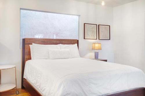 a bedroom with a large white bed with a window at Beachy Venice Bungelow off Abbot Kinney in Los Angeles