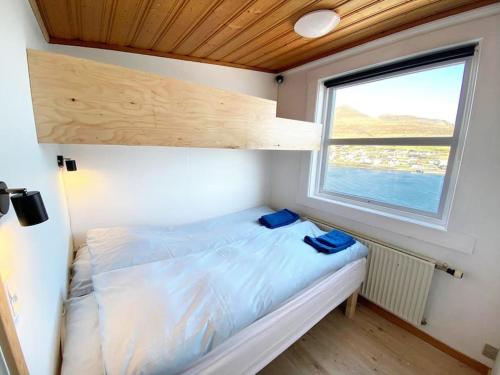 Ce lit se trouve dans une petite chambre dotée d'une fenêtre. dans l'établissement Oceanfront View Country House - (Airport 10 min.), à Sandavágur